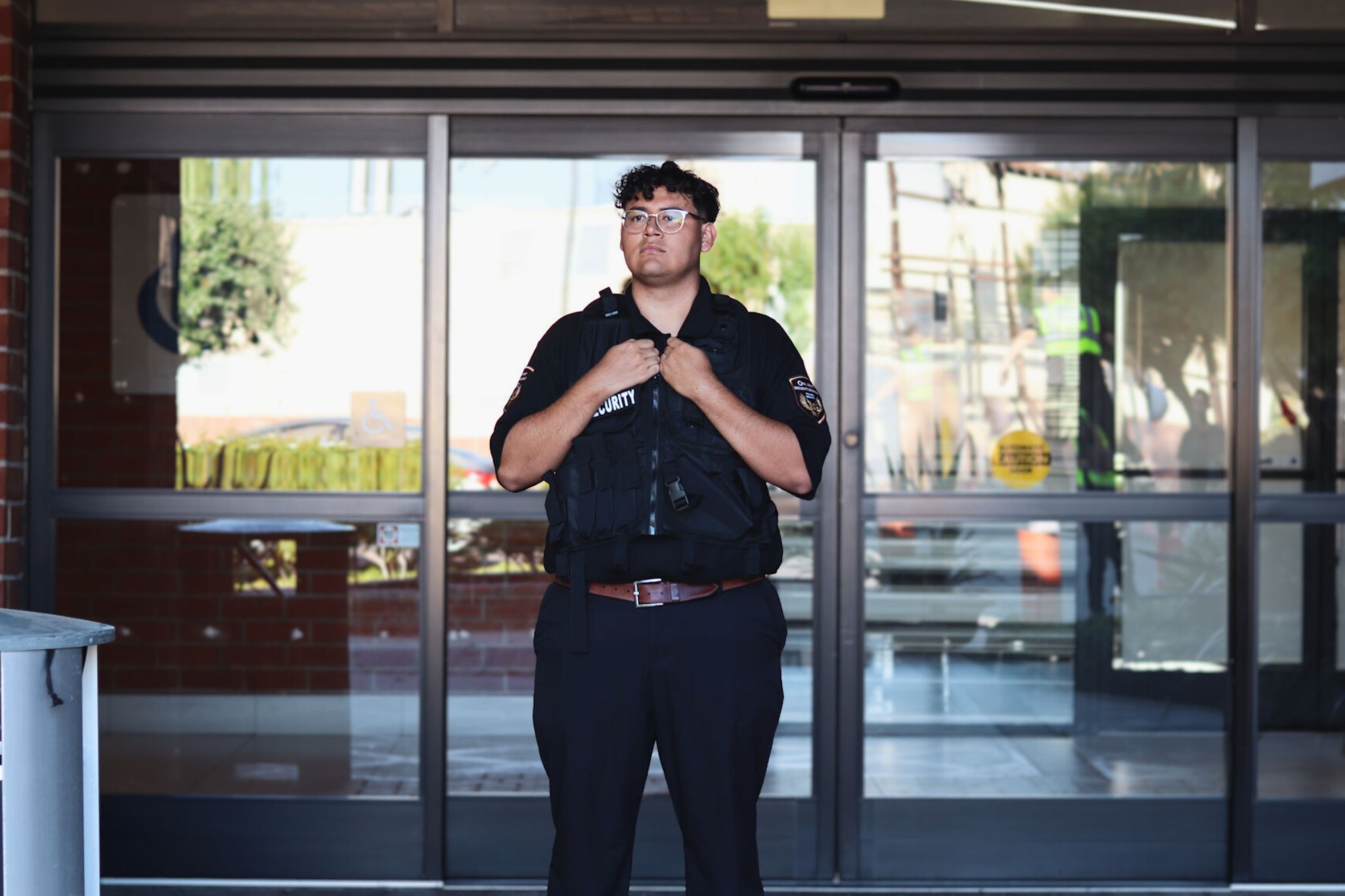 security guard standing by entrance with a security vest on