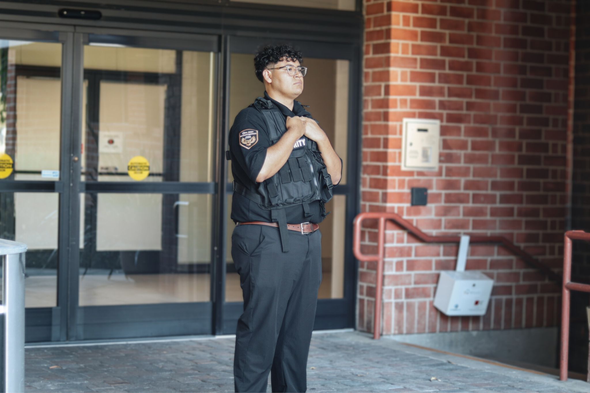 security guard standing by building entrance with a security vest on