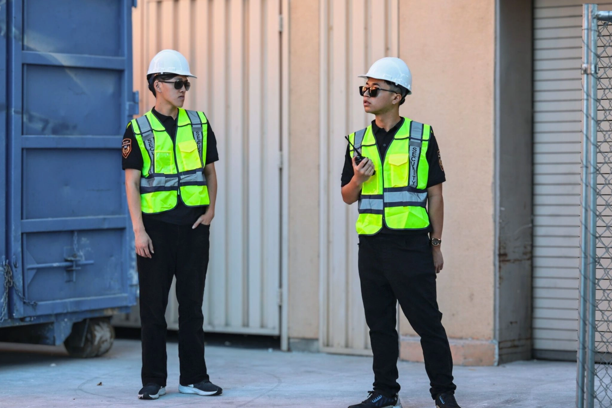 security guards wearing reflective vest and construction helmet talking to each other