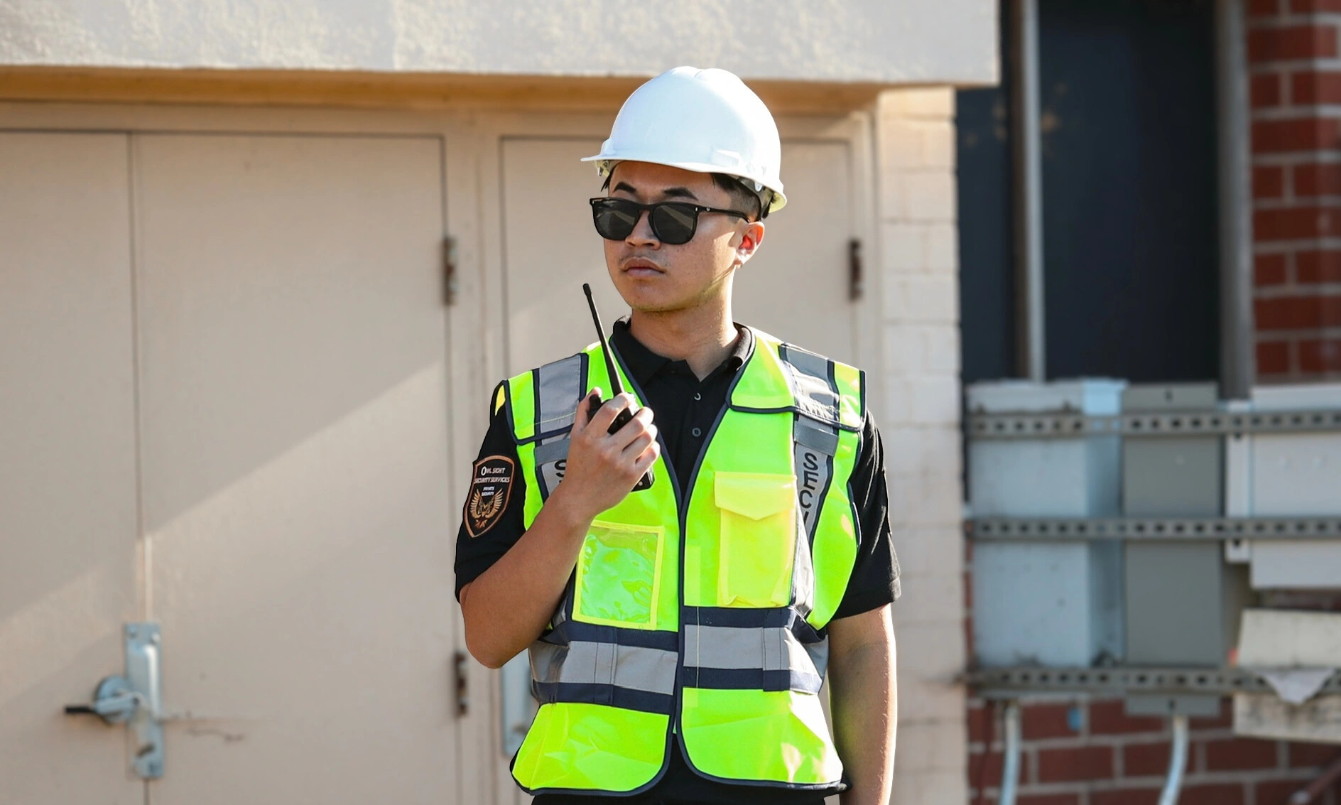 security guard wearing reflective vest and helmet holding a radio
